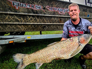 Guided bowfishing trip in Missouri – client holding a grass carp on Firehouse Bowfishing boat
